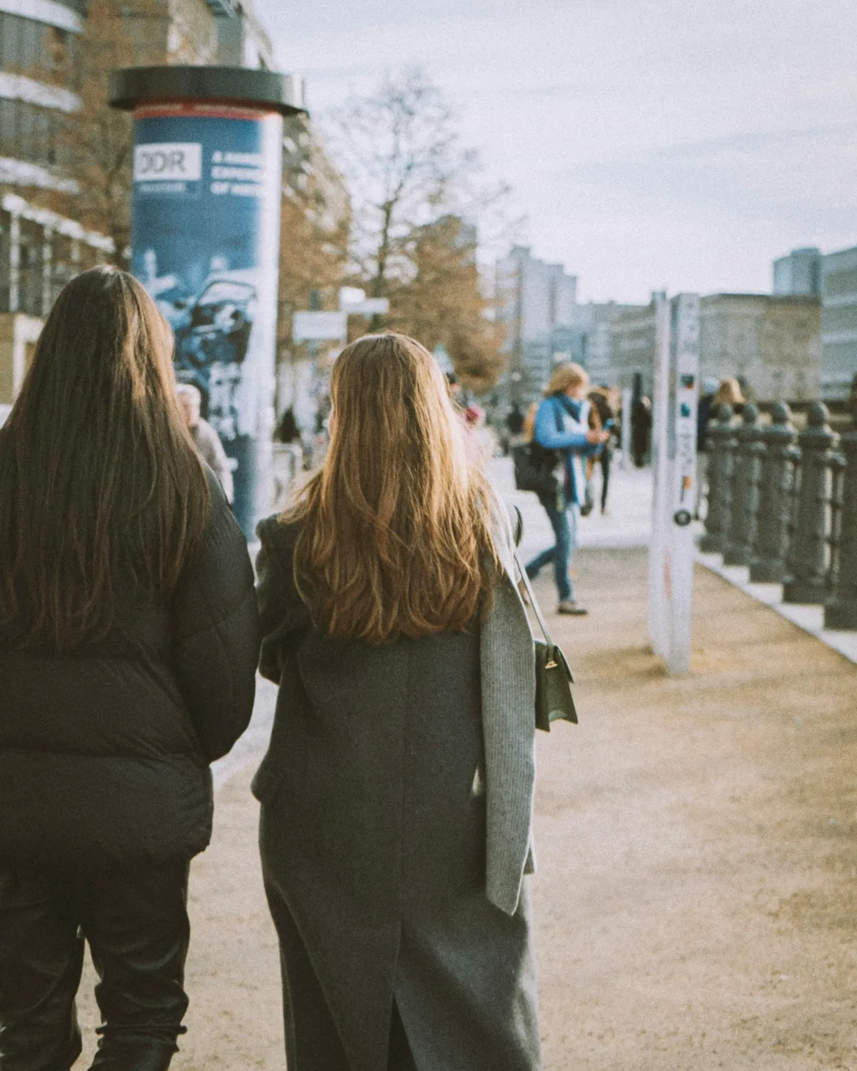 Twee vrouwen lopen naast elkaar over straat, van achteren gezien